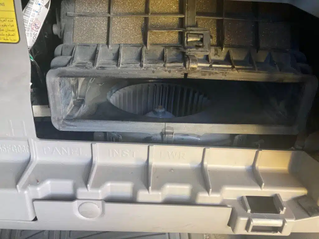 Close-up view of an empty slot behind the glove box, designated for the cabin air filter.