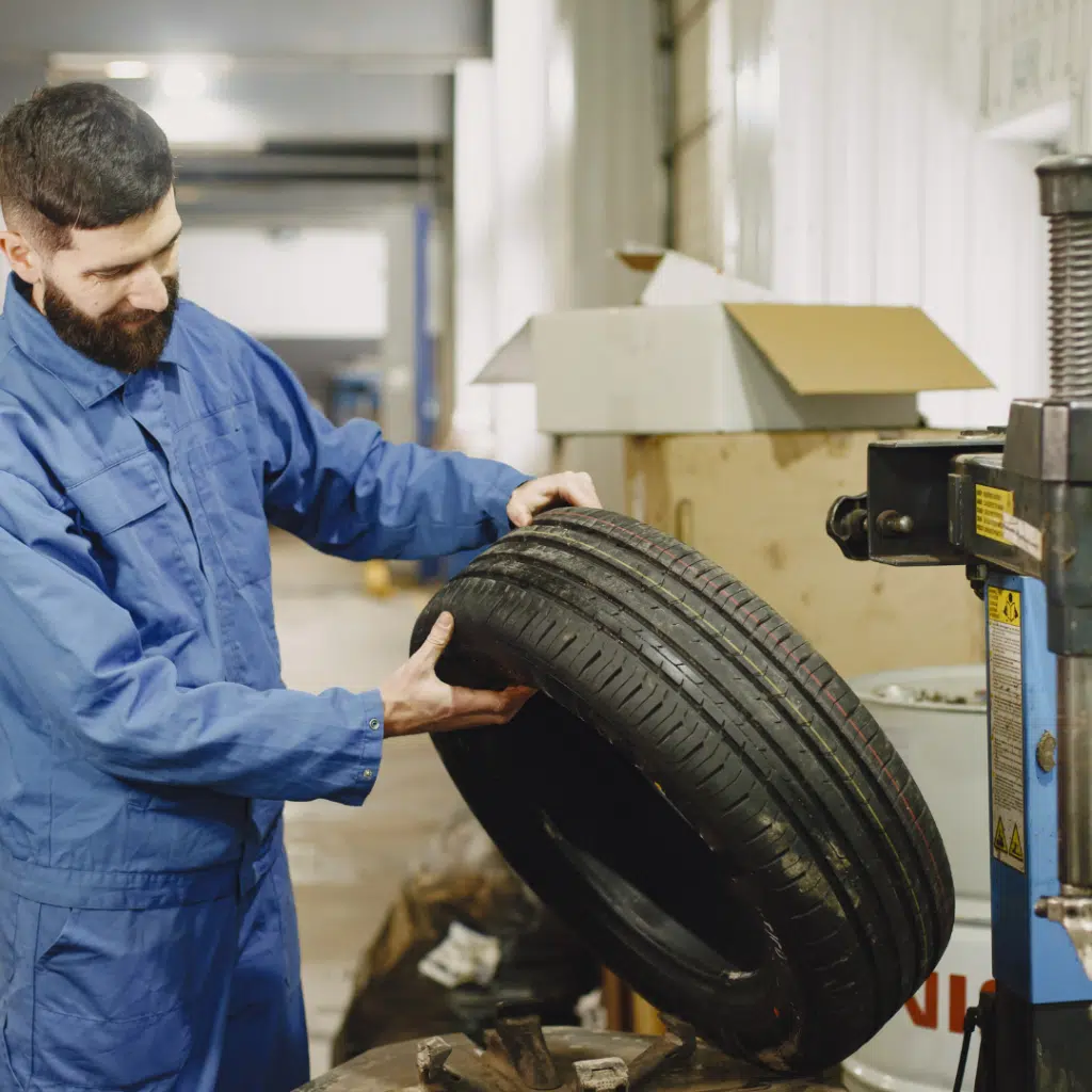 Mechanic inspecting a car tire for issues due to a humming noise